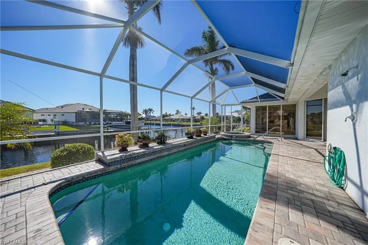View of swimming pool with a patio, a water view, and a lanai