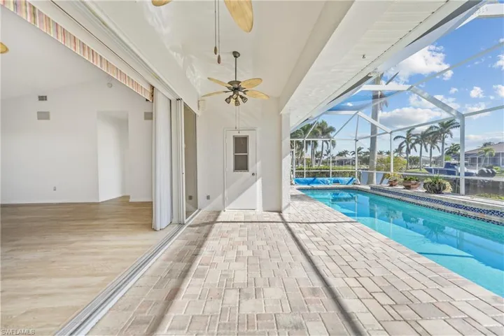 View of pool featuring glass enclosure, ceiling fan, and a patio area