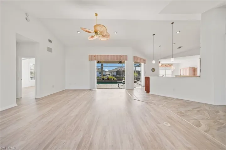 Unfurnished living room with ceiling fan, light wood-type flooring, and high vaulted ceiling