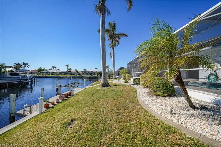 Dock area with a lawn, glass enclosure, and a water view