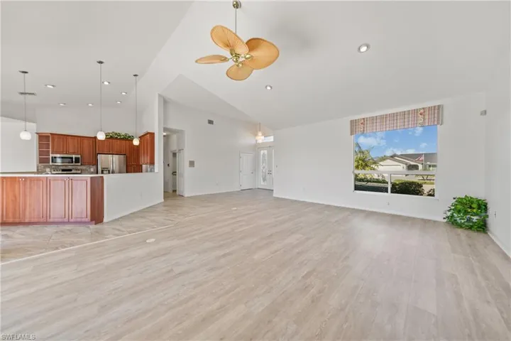 Unfurnished living room with ceiling fan, high vaulted ceiling, and light hardwood / wood-style floors