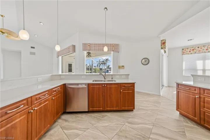 Kitchen featuring pendant lighting, dishwasher, sink, and vaulted ceiling