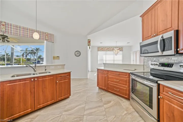 Kitchen with sink, stainless steel appliances, hanging light fixtures, and vaulted ceiling