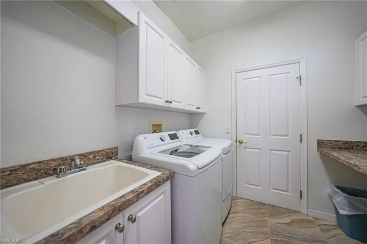 Clothes washing area with washing machine and dryer, sink, and cabinets