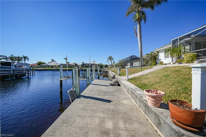 Dock area with a lanai, a water view, and a yard
