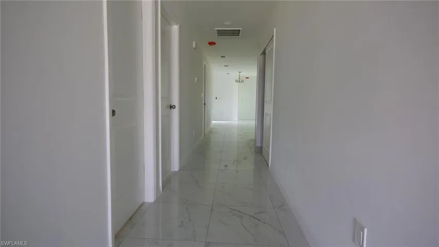 Corridor featuring marble finish floor, baseboards, and visible vents