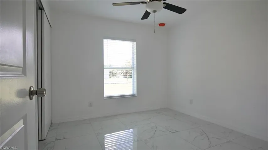 Empty room with a ceiling fan, marble finish floor, and baseboards