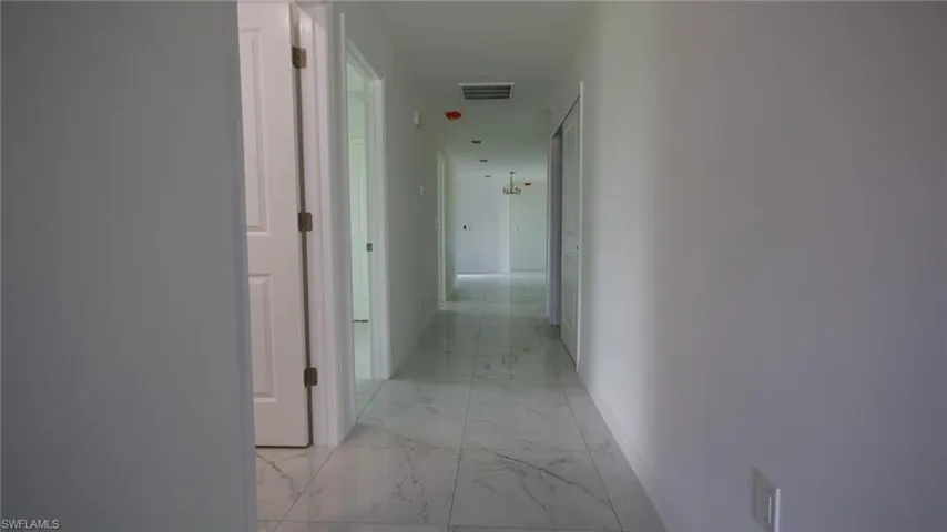 Corridor with marble finish floor, baseboards, and visible vents