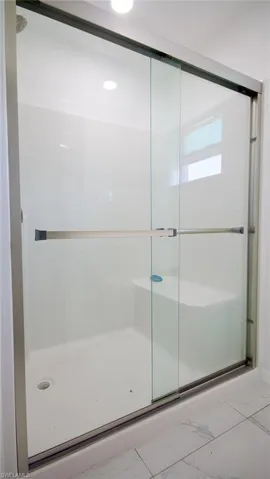 Bathroom featuring marble finish floor and a stall shower