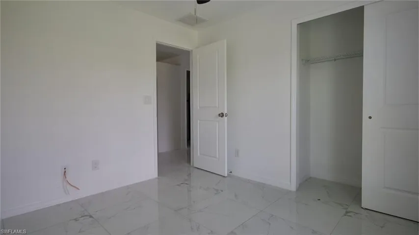 Unfurnished bedroom featuring baseboards, marble finish floor, visible vents, and a closet
