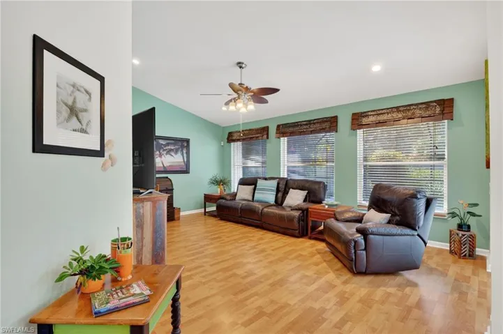Living room with light wood-type flooring, a ceiling fan, recessed lighting, and vaulted ceiling