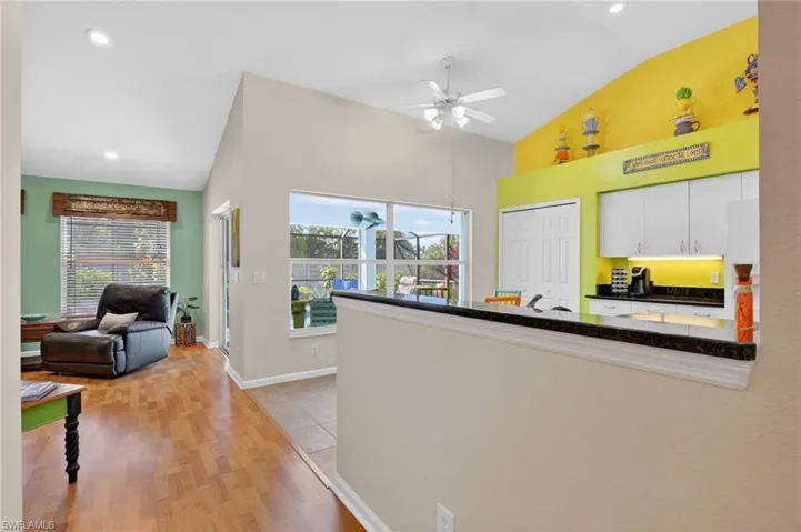 Kitchen featuring white cabinets, high vaulted ceiling, a ceiling fan, and light wood finished floors