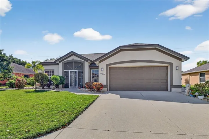 Ranch-style home with stucco siding, driveway, a front yard, and an attached garage