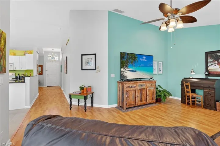 Living area featuring a towering ceiling, light wood-style floors, ceiling fan, and a chandelier