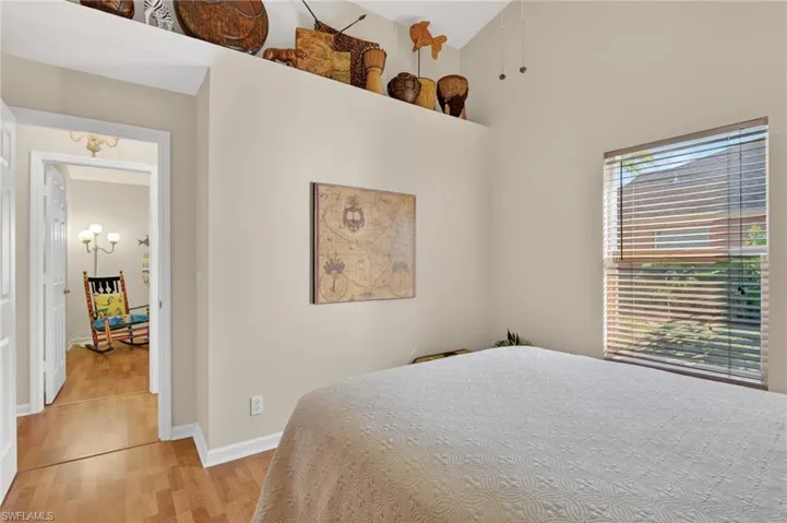 Bedroom featuring light wood-style floors, a high ceiling, and a chandelier