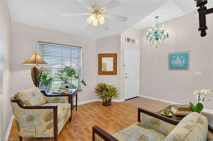 Sitting room with light wood-style floors, a ceiling fan, vaulted ceiling, and a chandelier