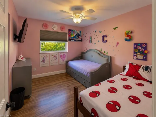 Wood-finish flooring, central ceiling fan with integrated lighting, and a window with a neutral roller shade