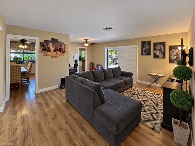 Wood-finish flooring, ceiling fan, and sliding glass doors with plantation-style shutters
