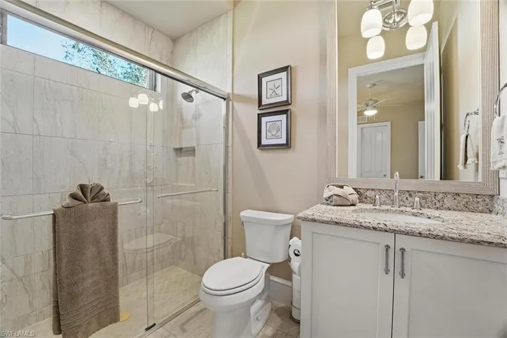 Bathroom with vanity, a shower stall, a ceiling fan, and a chandelier