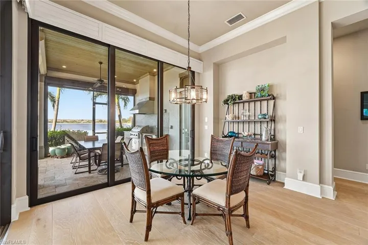 Dining space with a water view, light wood finished floors, crown molding, and a chandelier
