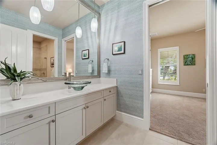 Bathroom featuring wallpapered walls, vanity, light tile patterned floors, and light colored carpet