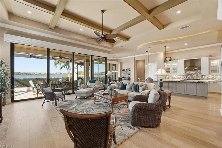 Living room with coffered ceiling, a water view, plenty of natural light, beamed ceiling, and light wood-style floors