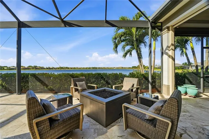 View of patio / terrace with a sunroom, a lanai, a water view, and an outdoor fire pit