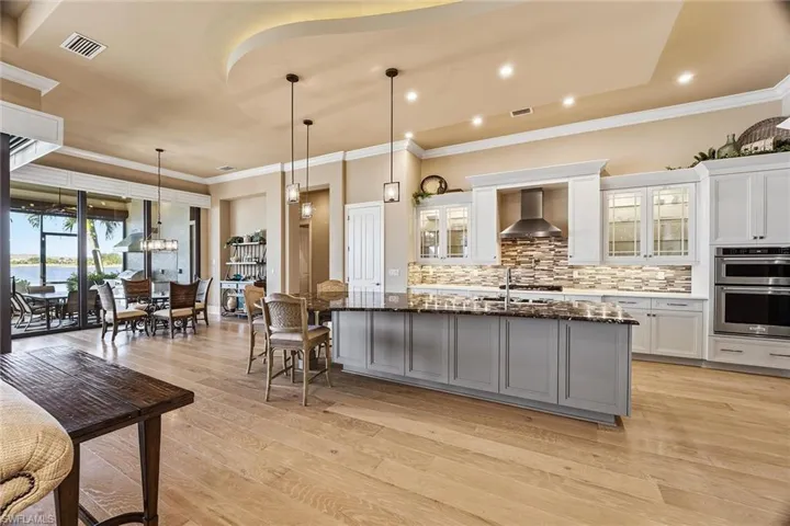Kitchen featuring glass insert cabinets, white cabinets, pendant lighting, and crown molding