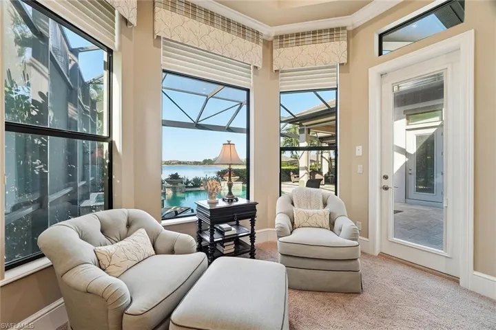 Living area featuring a sunroom, a water view, ornamental molding, plenty of natural light, and carpet floors