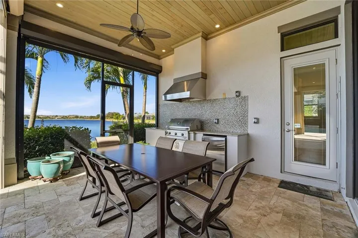 View of patio / terrace featuring outdoor dining area, a ceiling fan, a water view, area for grilling, and a sunroom