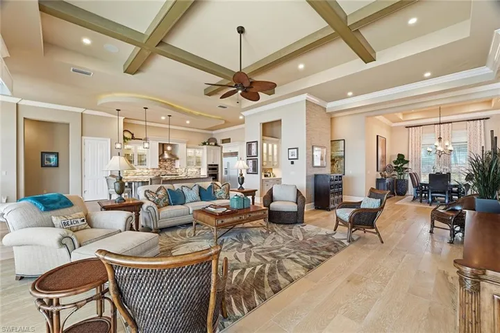 Living room with coffered ceiling, ceiling fan, light wood-type flooring, recessed lighting, and a chandelier