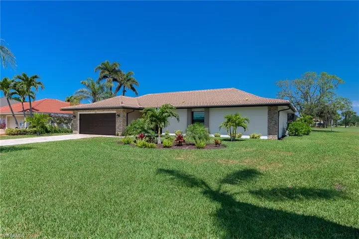 View of front of house with a tile roof, a garage, concrete driveway, and a front yard