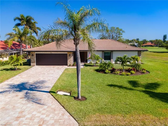 View of front of house featuring an attached garage, a tile roof, a front yard, and decorative driveway