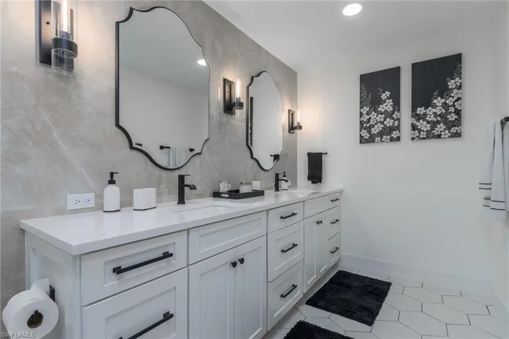 Bathroom with tile walls, double vanity, a sink, and tile patterned floors