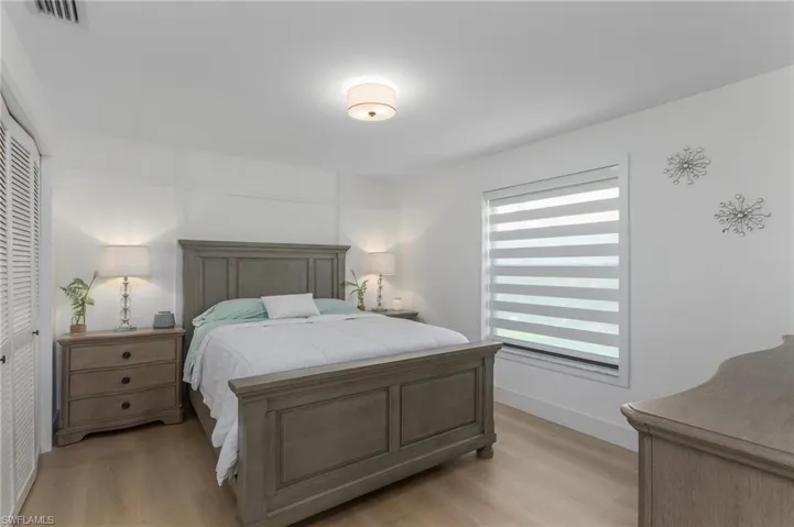 Bedroom with light wood-type flooring, baseboards, a closet, and visible vents