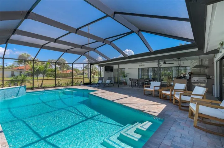 Pool featuring a patio, grilling area, outdoor dining area, glass enclosure, and an outdoor kitchen