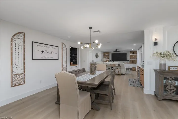 Dining room featuring light wood-style flooring, ceiling fan with notable chandelier, baseboards, and visible vents