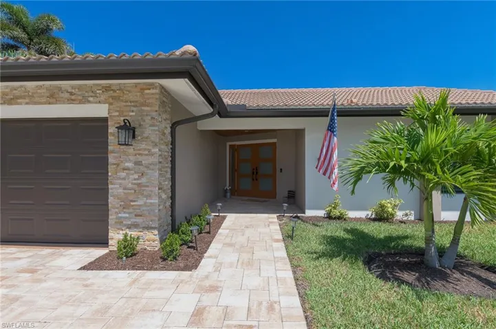 Entrance to property featuring a tile roof, stucco siding, french doors, stone siding, and a garage