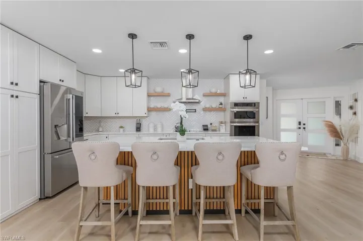 Kitchen featuring visible vents, open shelves, white cabinetry, and stainless steel appliances