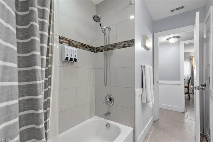 Bathroom with soap, shampoo, and conditioner dispenser making the home ready to go as an investment or vacation home!  New patterned tile throughout makes cleaning convenient.