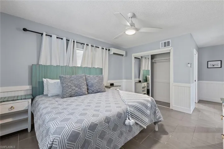 Primary bedroom with private bathroom. This room has a separate mini split cooling system adding comfort and control over your specific sleeping temperature.  Impact windows and sliding glass door to the pool.
