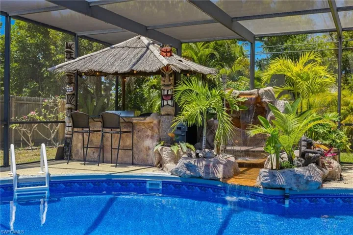 You'll love the pool side tiki bar, outdoor kitchen, custom waterfall, and tropical stream with wooden bridge into the pool.