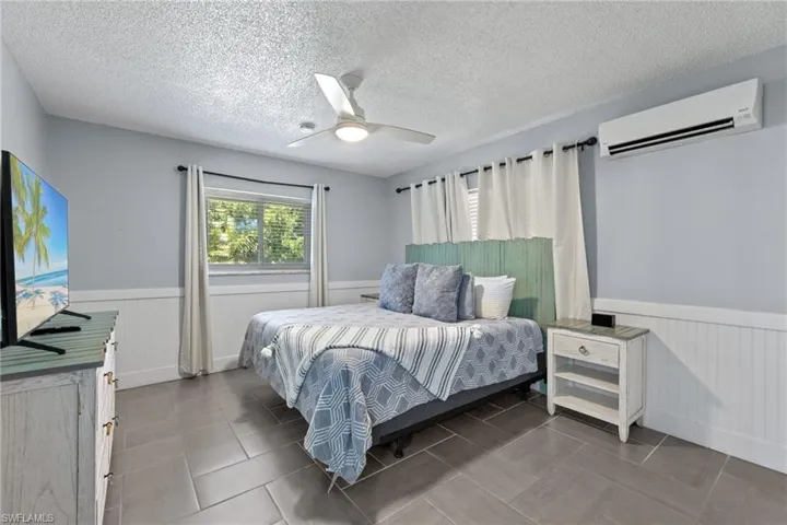 Primary bedroom with tile floors, matching bedroom set, impact windows, and separate mini-split ac system add comfort and economical cooling being that you can set the AC lower in your bedroom than the rest of the house.