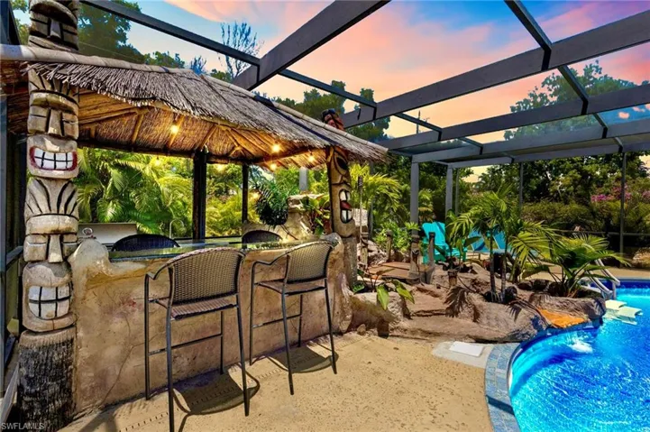 Custom built tiki bar, rock grotto waterfall with stream into the pool, and outdoor kitchen.  The unique pool cage is built with reinforced aluminum members to add more height in the back of the lanai to create an open outdoor living space.  Enjoy incredible sunsets with this homes Western rear exposure.