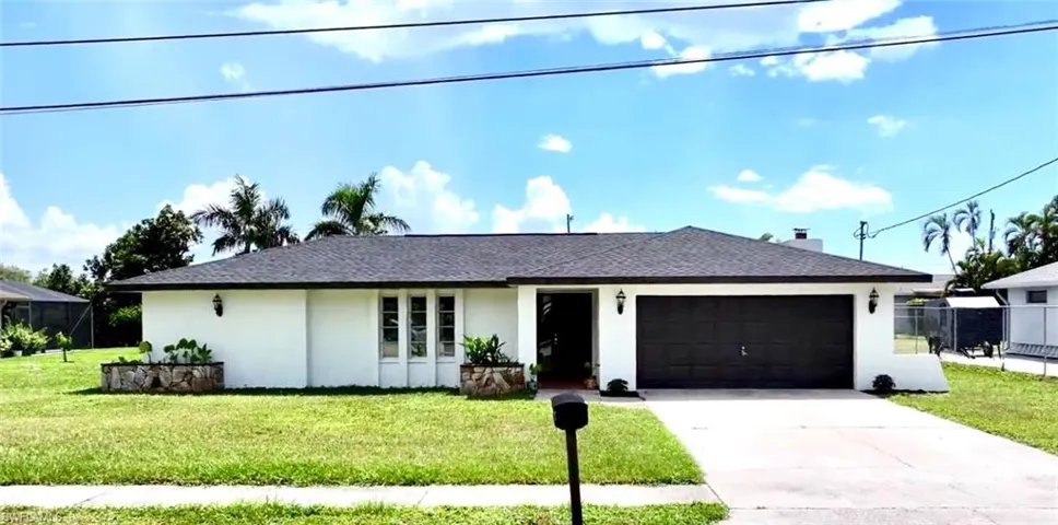Single story home with a garage and a front lawn