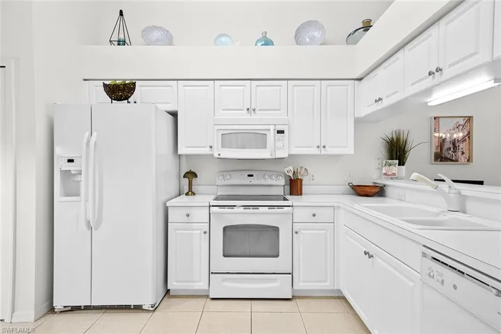 Kitchen featuring white appliances, white cabinetry, light countertops, and light tile patterned floors