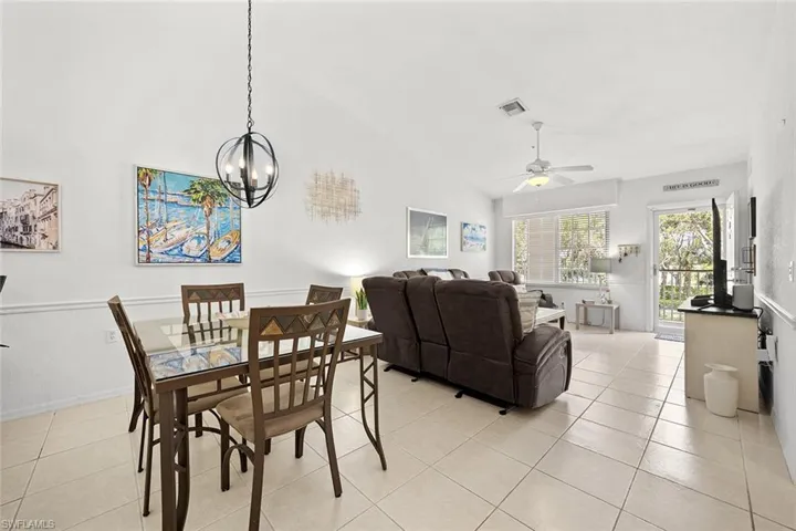 Dining space featuring ceiling fan, light tile patterned floors, hanging lights, and vaulted ceiling