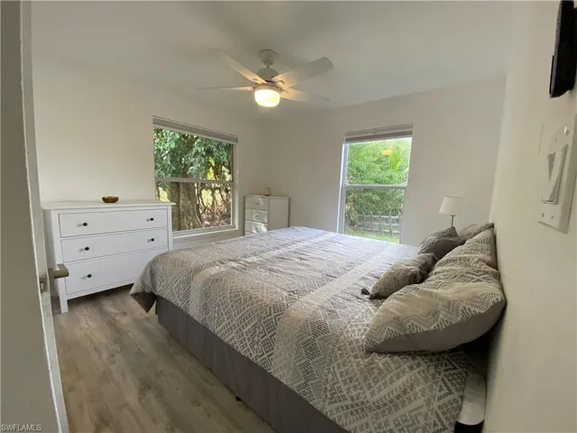 Bedroom featuring multiple windows, wood finished floors, and a ceiling fan