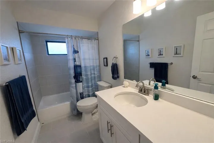 Bathroom featuring shower / tub combo, vanity, light tile patterned flooring, and a textured wall