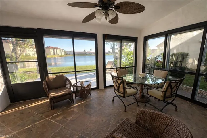 Sunroom featuring a water view, vaulted ceiling, and stone tile flooring